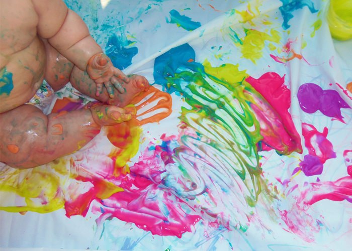 Image shows a baby playing with non-toxic paint. Idea from I heart arts and crafts