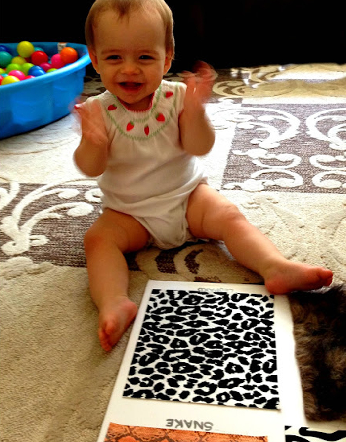 Image shows a toddler playing with an animal texture board. From House of Burke