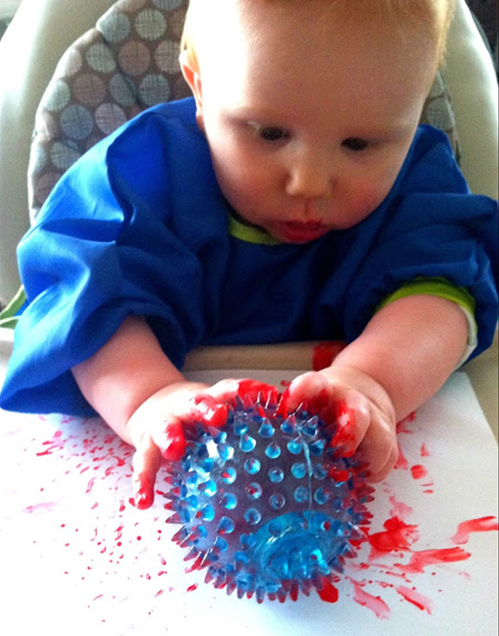 Image shows a toddler doing spiky ball painting. From House of Burke