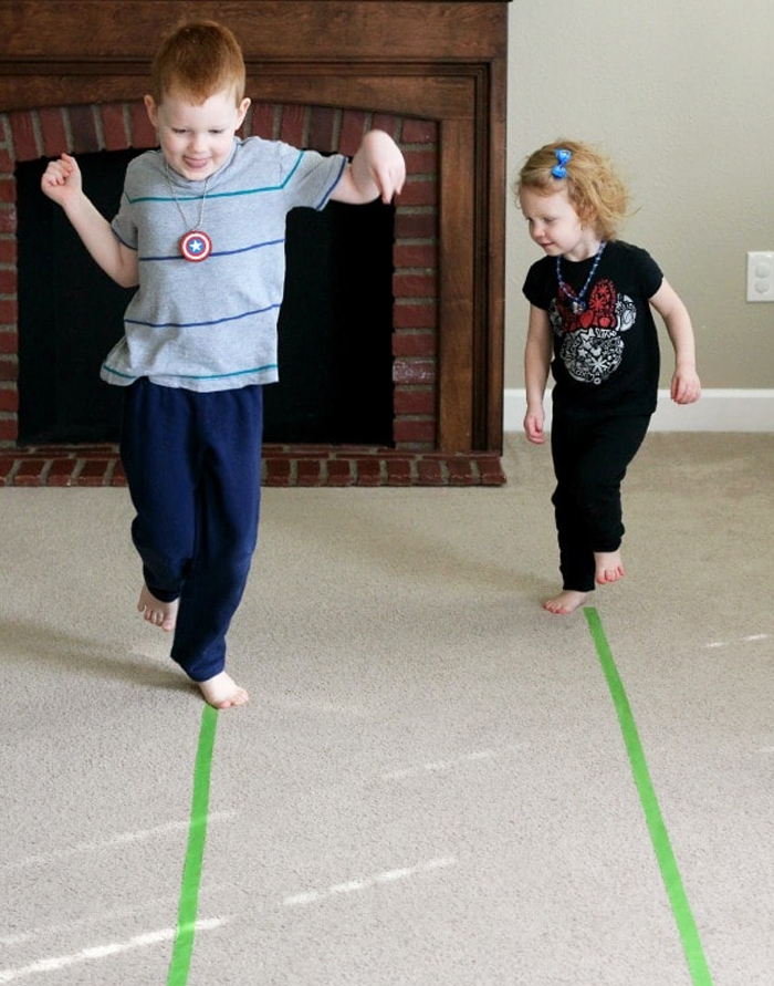 Image shows two kids plying a movement game indoors with scotch tape. Idea from Fun learning for kids