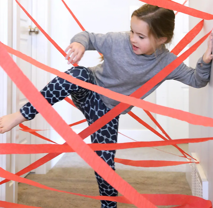 Image shows a kid playing in a DIY hallway laser maze indoors. From Its always autumn.