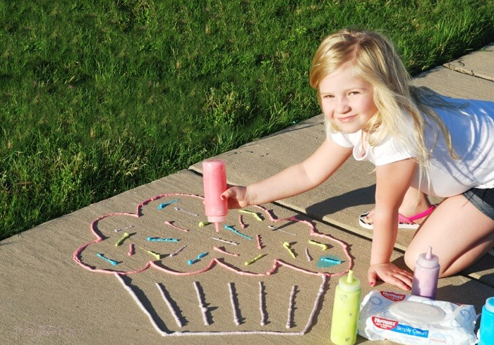 Image shows a young girl drawing a cupcake on the sidewalk with foam paint. Idea from The Tip Toe Fairy